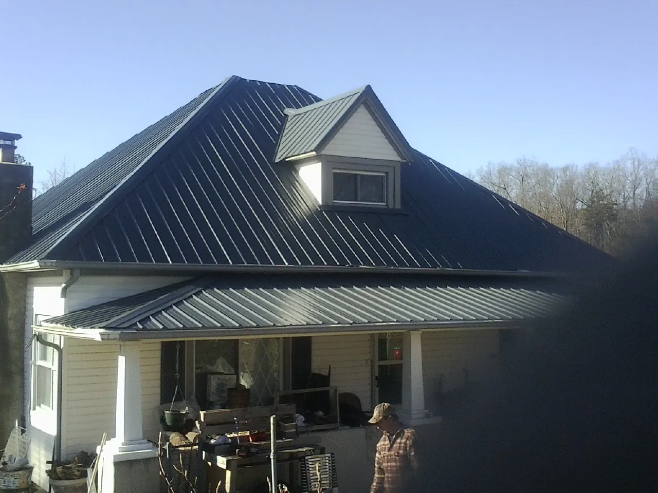 Dark blue standing seam metal roof with a dormer above a front porch in Tarzana