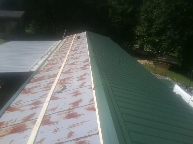 Old rusted panels beside newly installed green metal roofing — Wind Damage Roof Repair by Roofing Brothers in Tarzana