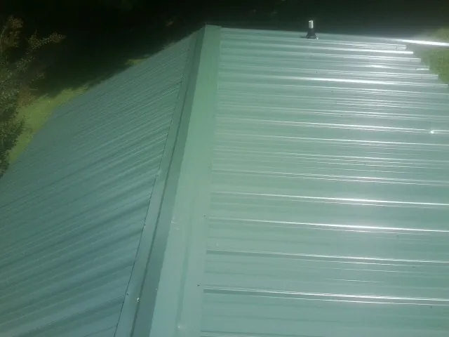 New green metal panels meeting at the ridge of a roof — Flat Roof Repair work by our crew in Tarzana