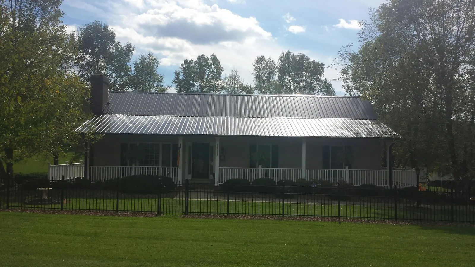 Gray metal roof on a brick ranch with a full width front porch — Gutter Guard Installation work by our crew in Tarzana