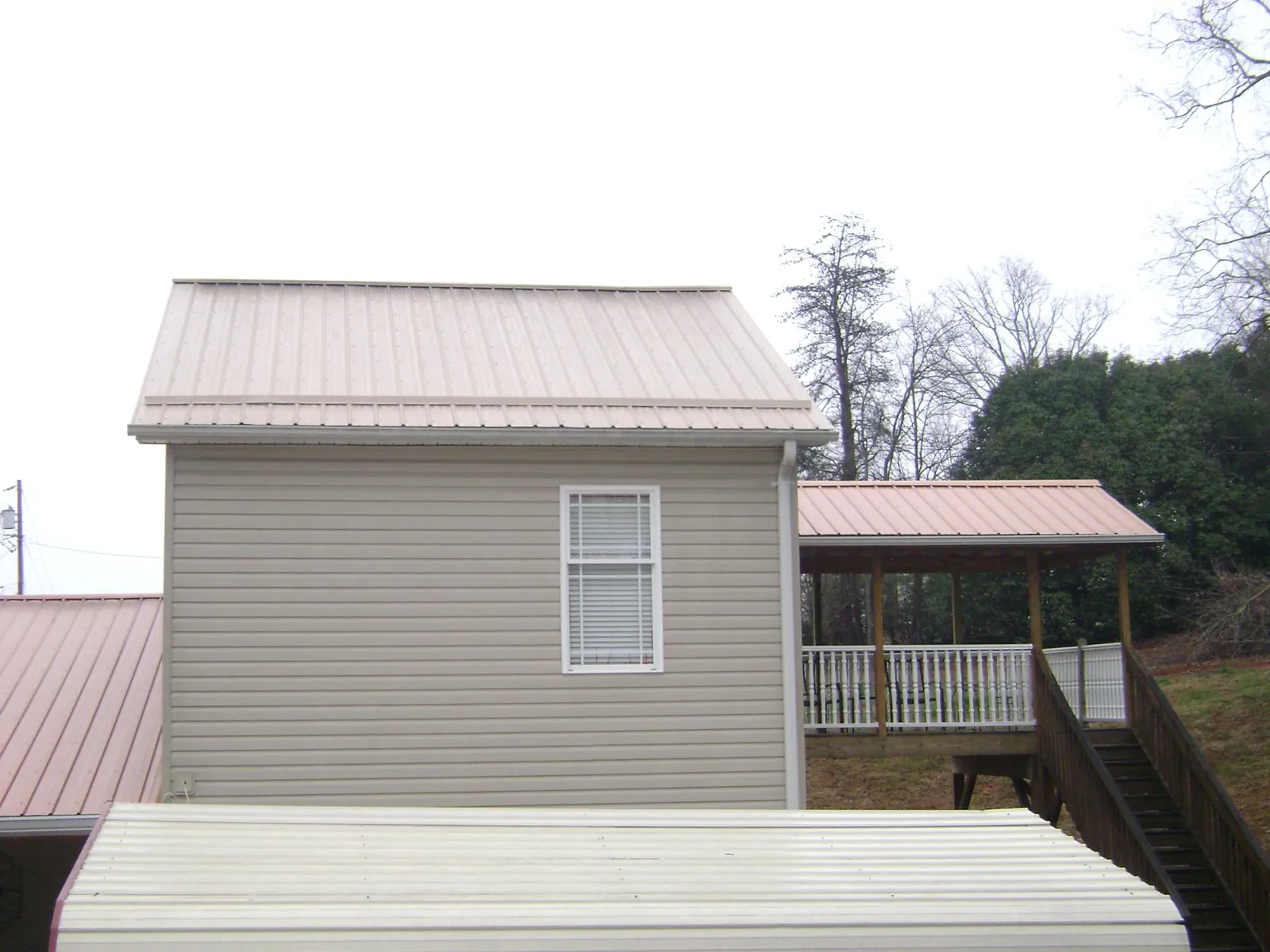 Tan metal roofs on a two story addition and attached porch, from a Roof Replacement job in Tarzana
