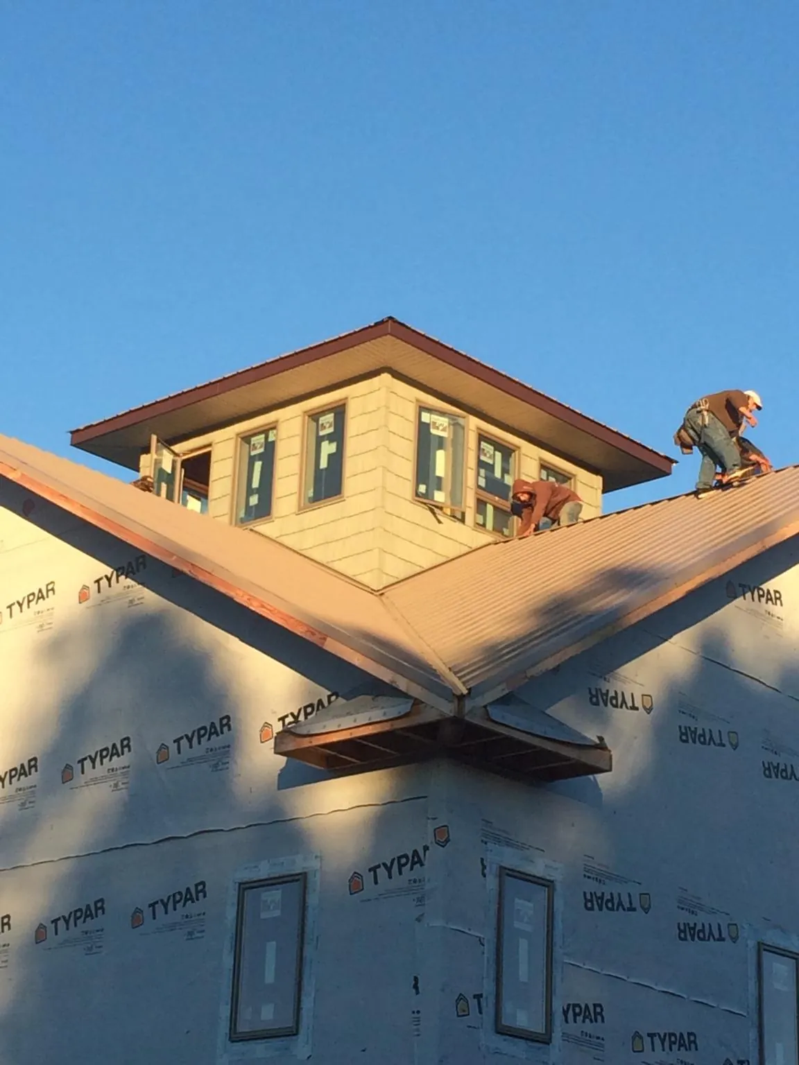 Roofers working around a rooftop cupola on a new metal roof at sunset — Roof Waterproofing in Tarzana by Roofing Brothers
